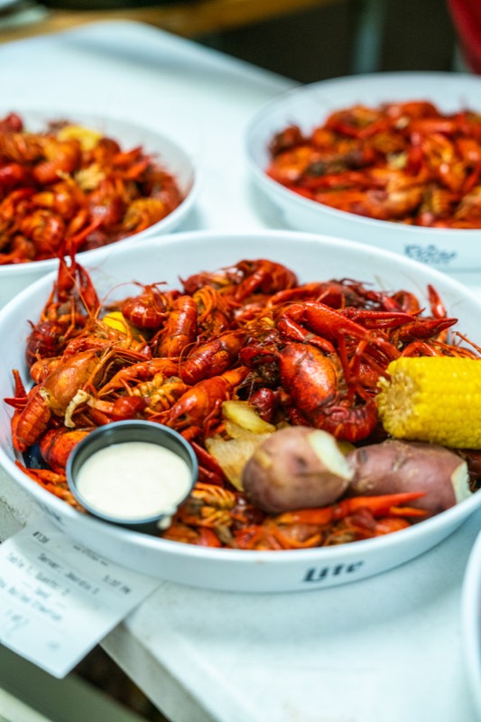 A tray of boiled crawfish with corn, potatoes and dipping sauce